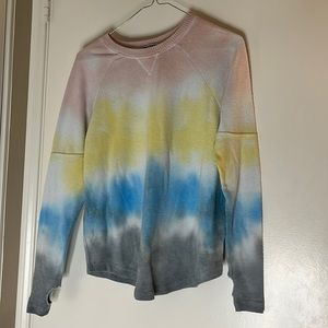 Tie dye sweater with thumb holes cut out on the sleeves.